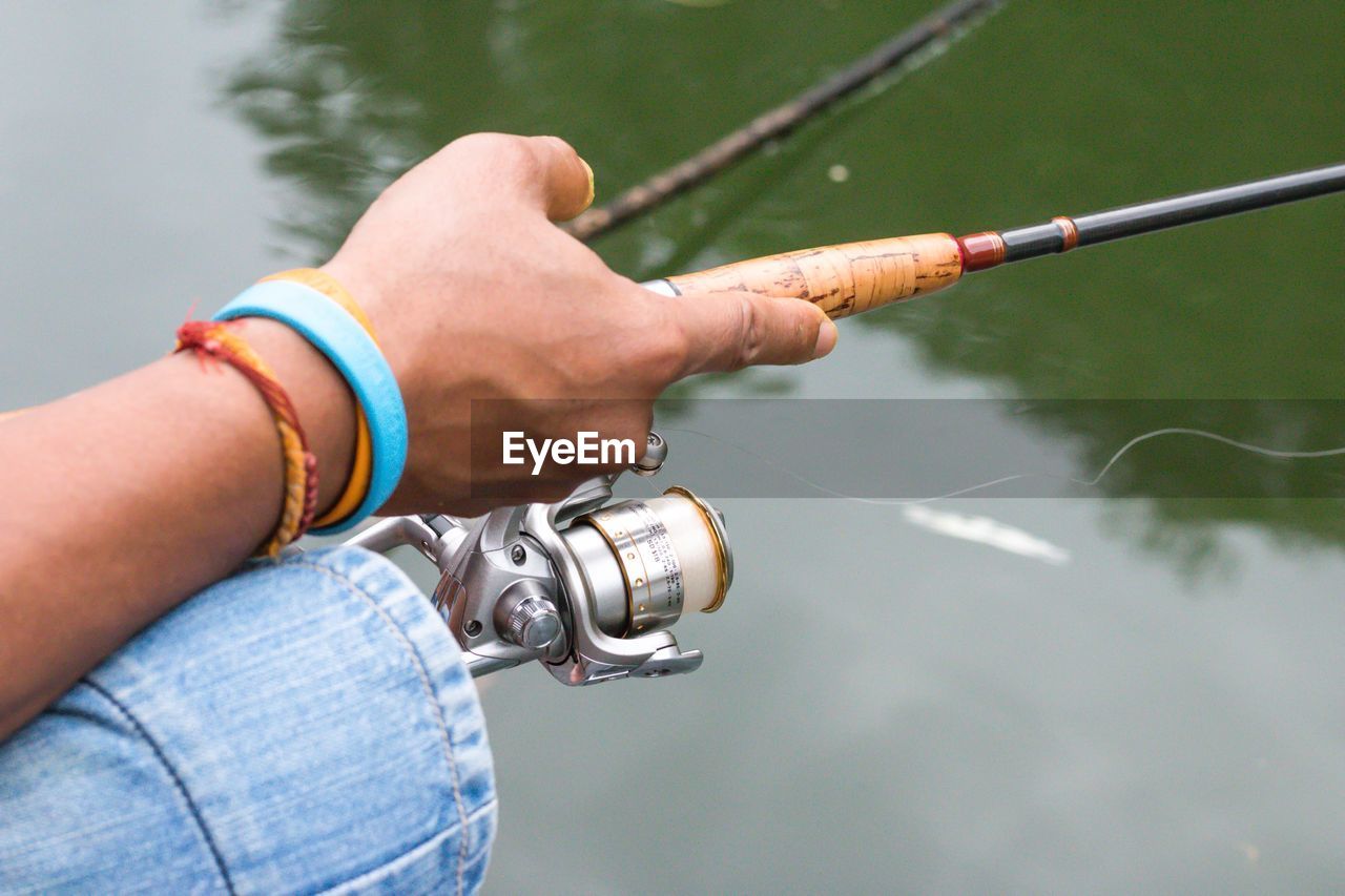 Midsection of man holding fishing rod