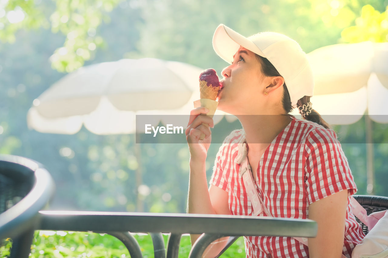 Woman eating ice cream while sitting at outdoors cafe