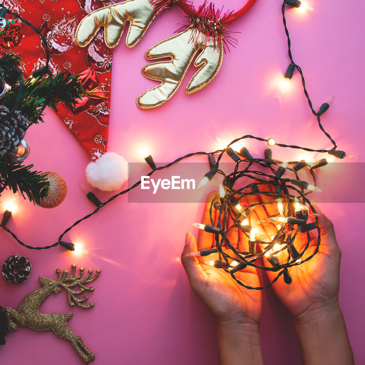 Cropped image of woman holding christmas decoration with various objects on table