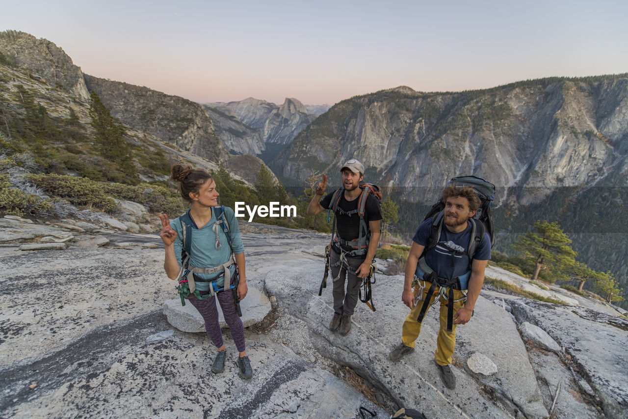 Three hikers at the top of el capitan in yosemite valley at sunset