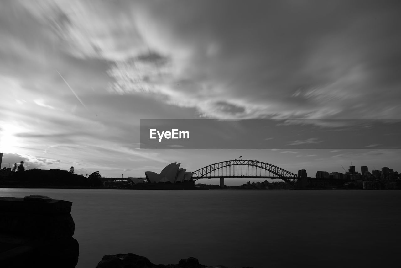 Sydney opera house and bridge over bay against sky