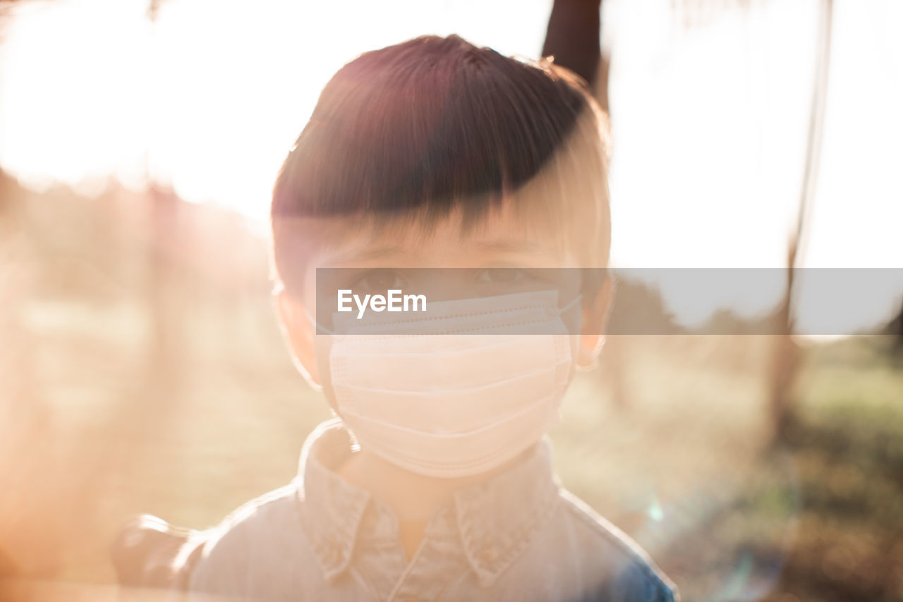 Portrait of boy wearing mask in forest on sunny day