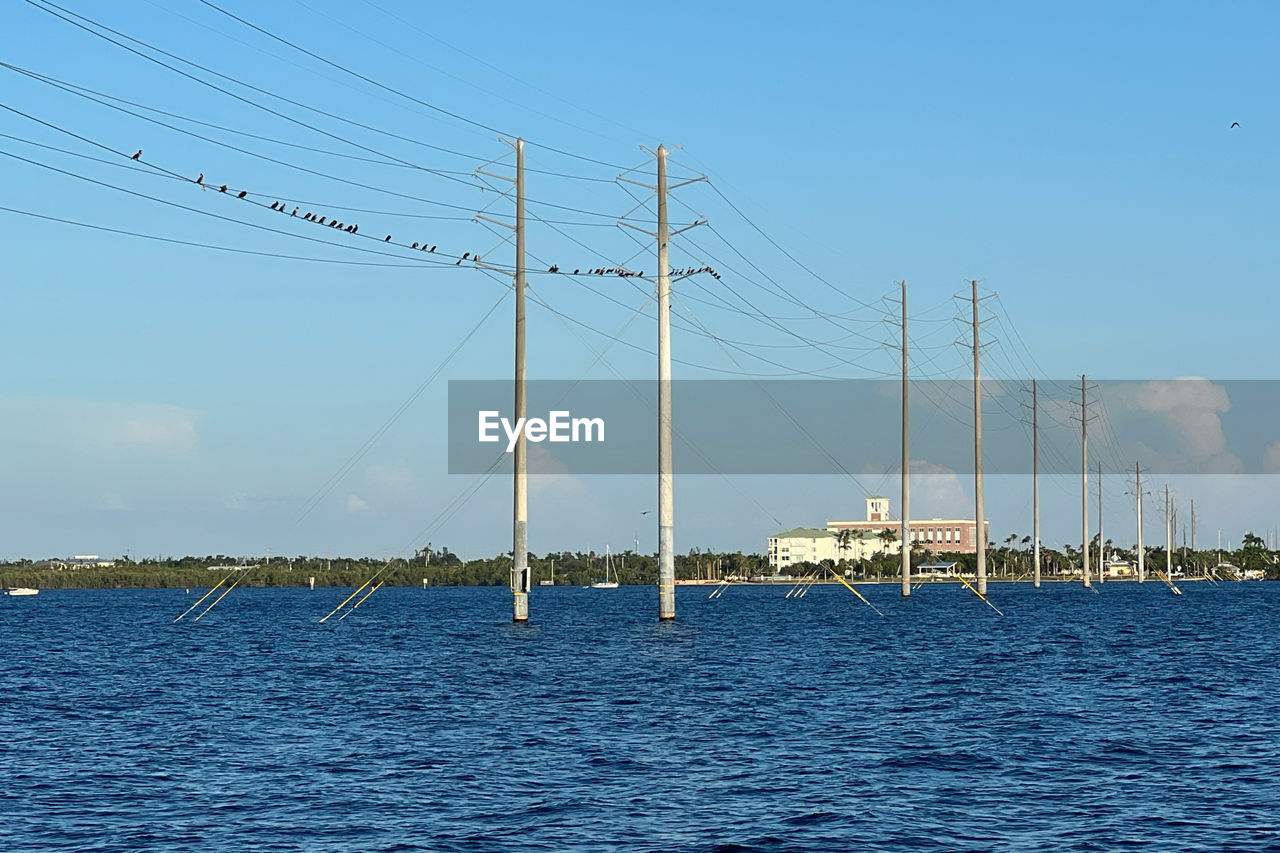 water, sky, sea, nature, cable, mast, transportation, electricity, no people, blue, day, sailboat, nautical vessel, technology, outdoors, mode of transportation, beauty in nature, pole, scenics - nature, power generation, horizon, vehicle, electricity pylon, architecture, sailing, power line, tranquility, power supply, travel, clear sky, tranquil scene, wind, cloud, ocean, environment, built structure, tower, travel destinations, dock