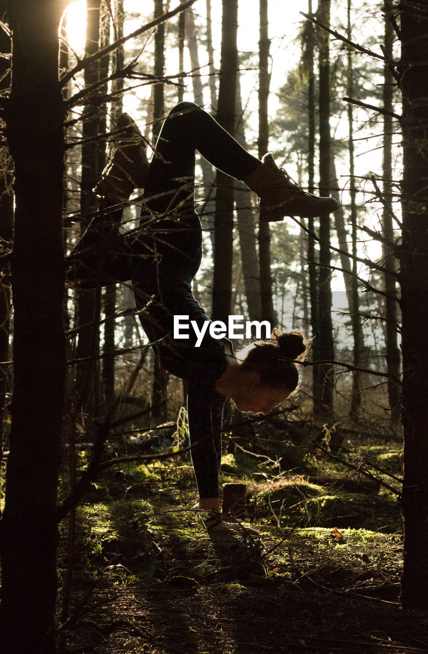 Woman doing handstand in forest