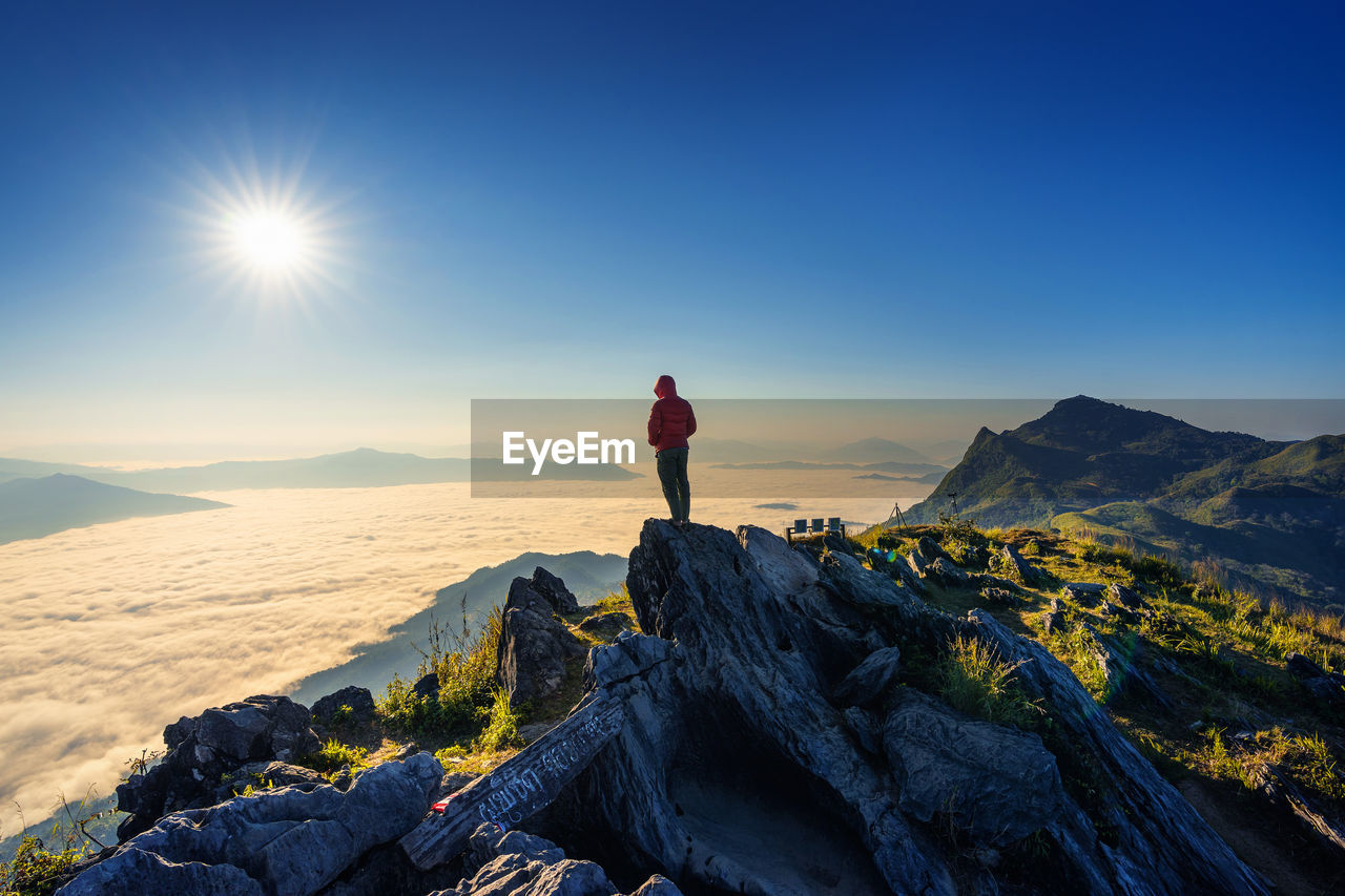 Person standing on rock at beach against sky