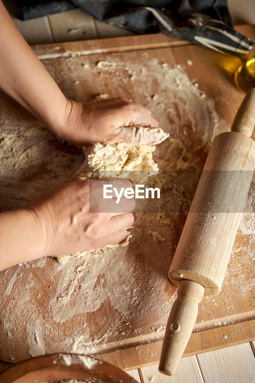 MIDSECTION OF PERSON PREPARING FOOD AT KITCHEN