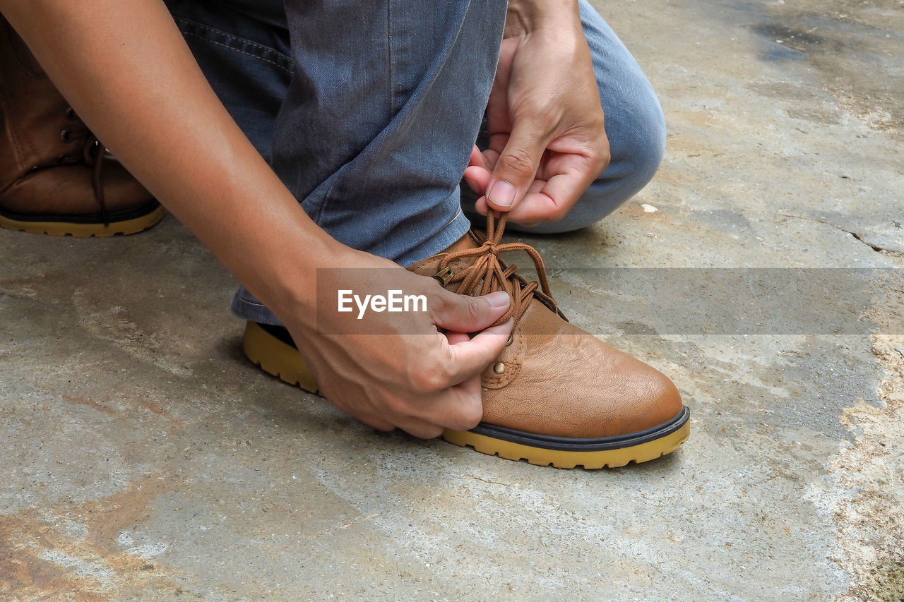 Low section of person tying shoelace