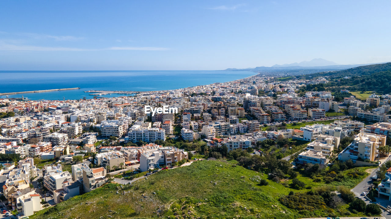 HIGH ANGLE SHOT OF TOWNSCAPE AGAINST SEA