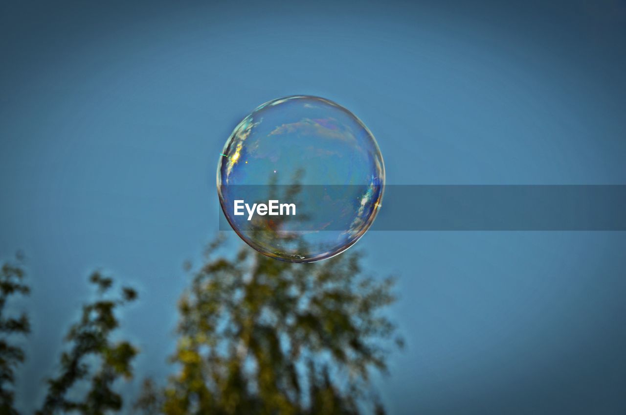 LOW ANGLE VIEW OF BUBBLES AGAINST CLEAR BLUE SKY