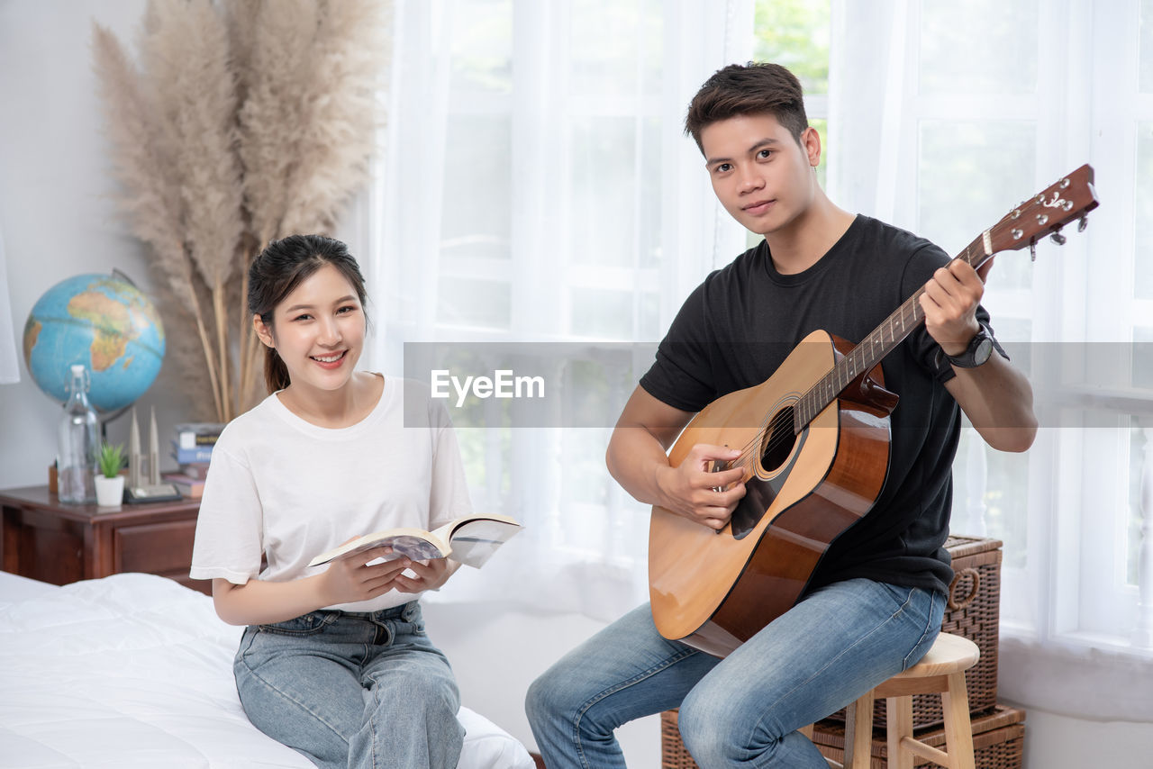 PORTRAIT OF SMILING MAN PLAYING GUITAR AT MUSIC