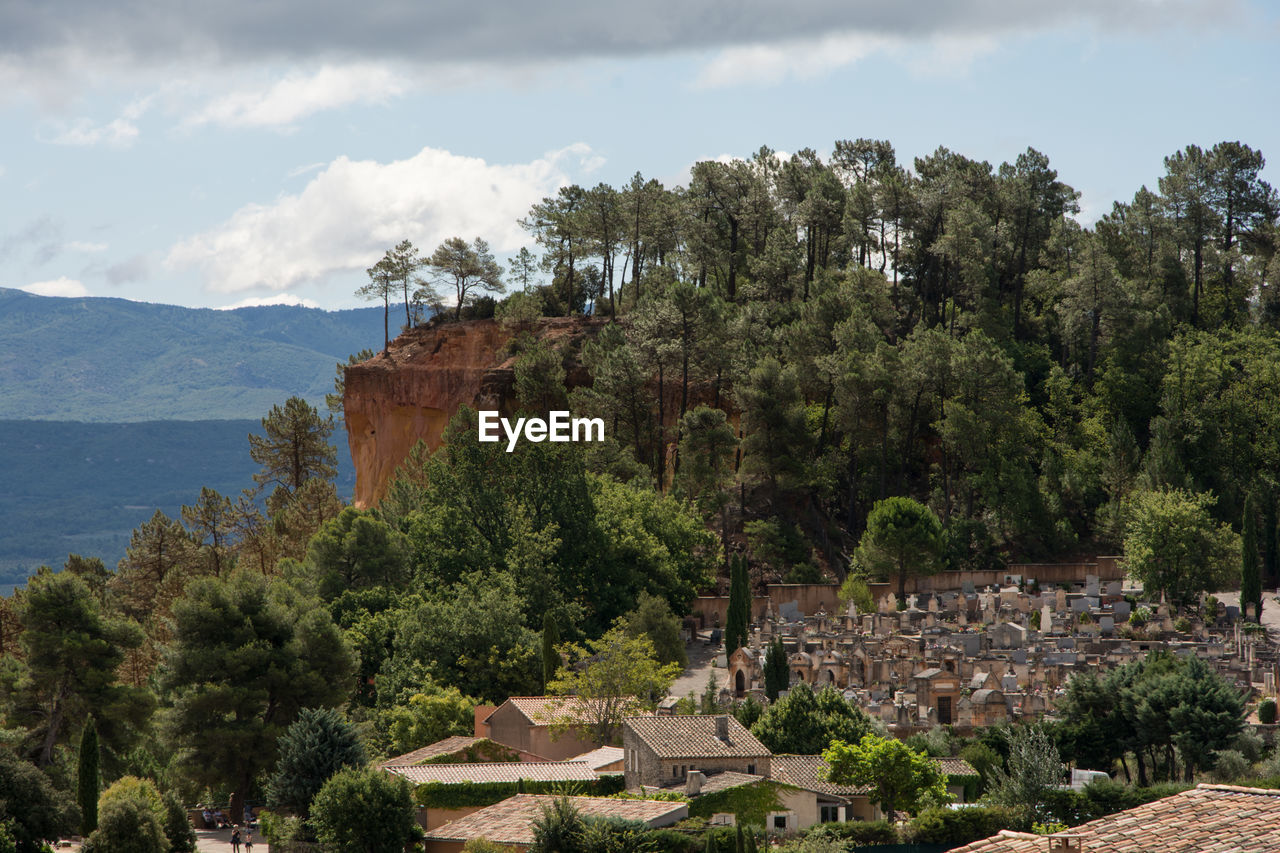 TOWN BY TREES AND MOUNTAINS AGAINST SKY