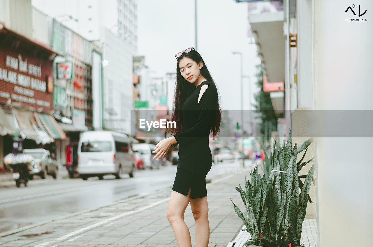 FULL LENGTH OF WOMAN STANDING AGAINST CITY