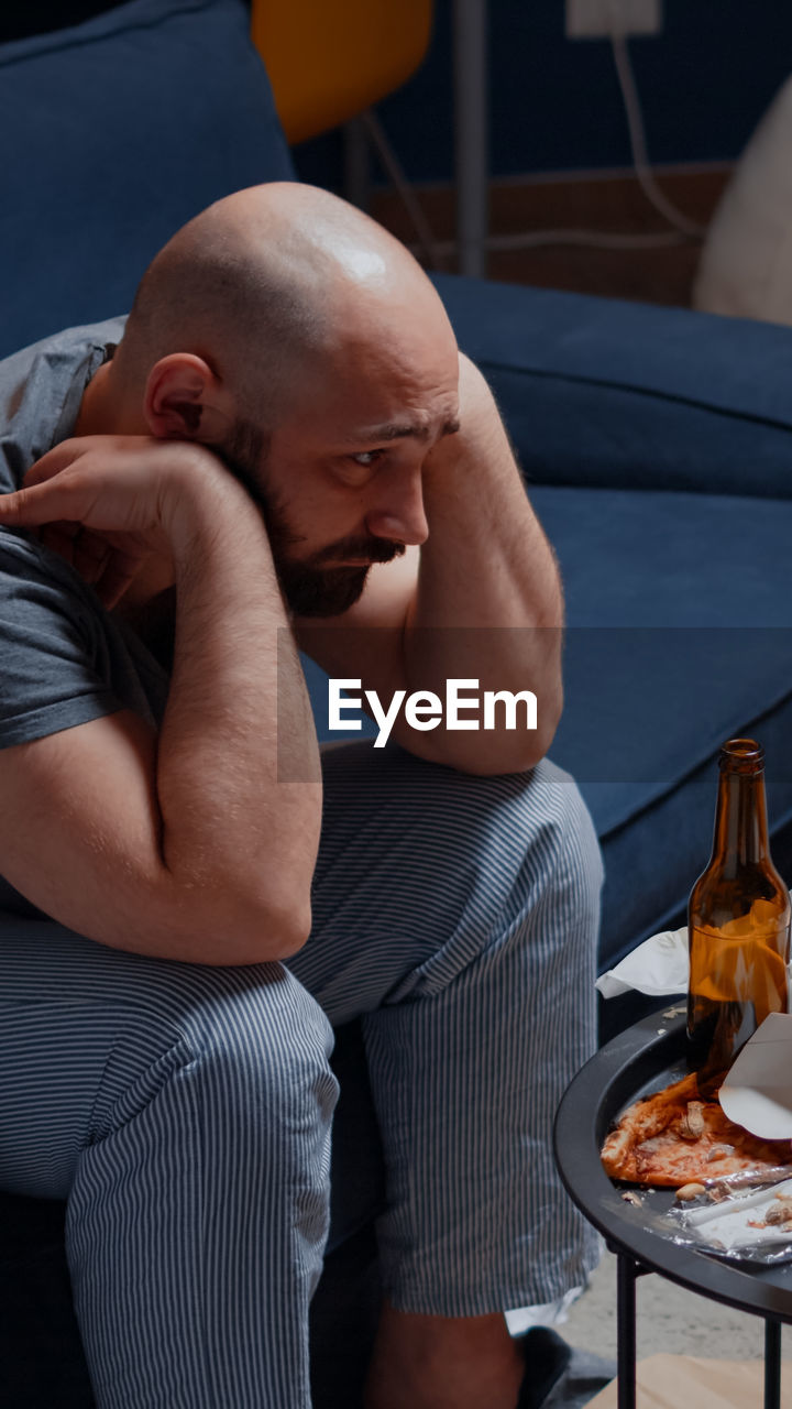 Depressed man sitting on sofa at home