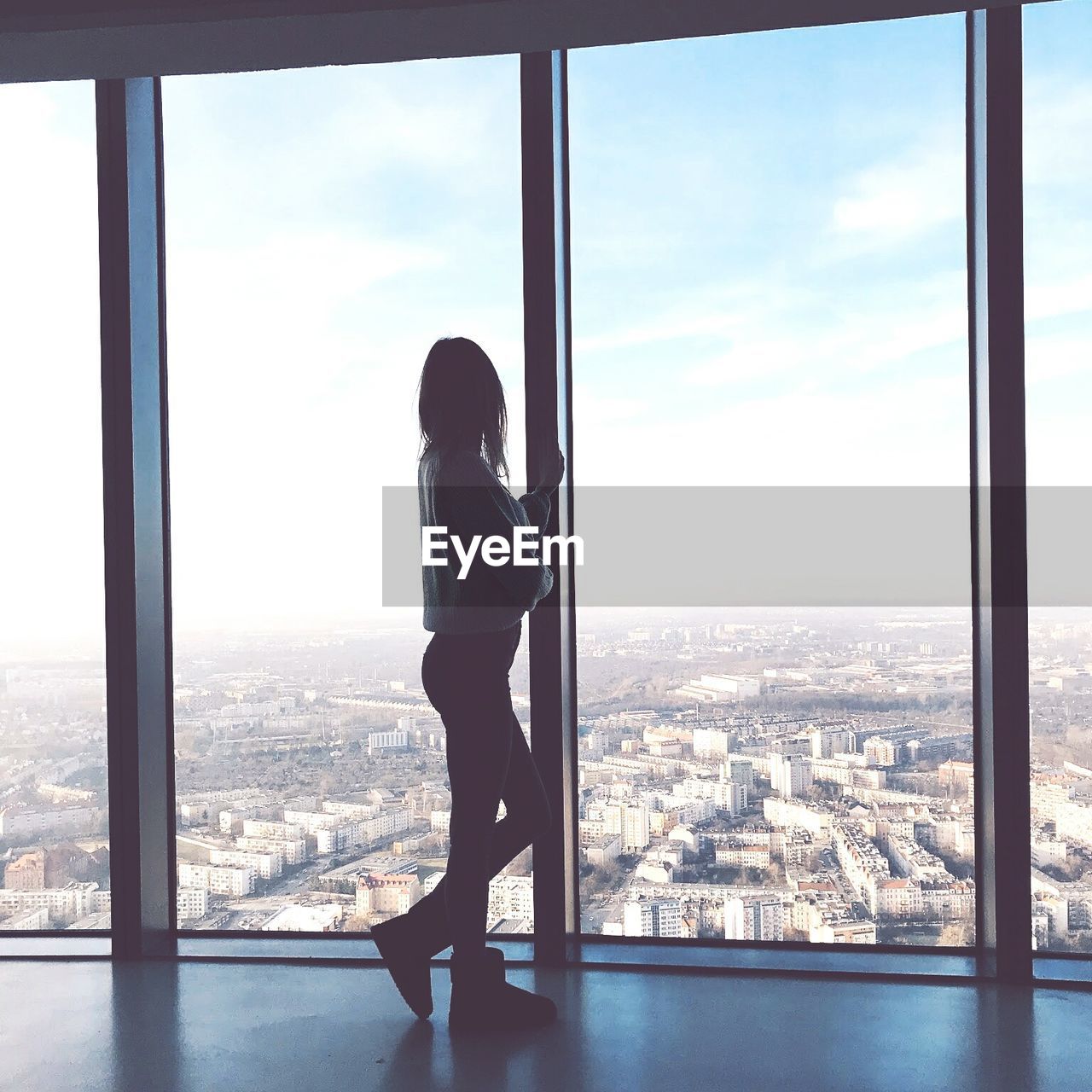 Woman looking at cityscape through window
