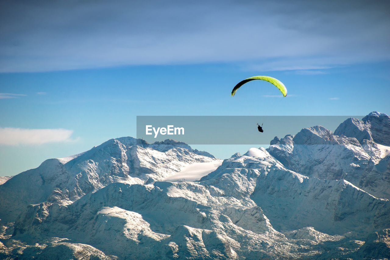 Person paragliding by snowcapped mountains 