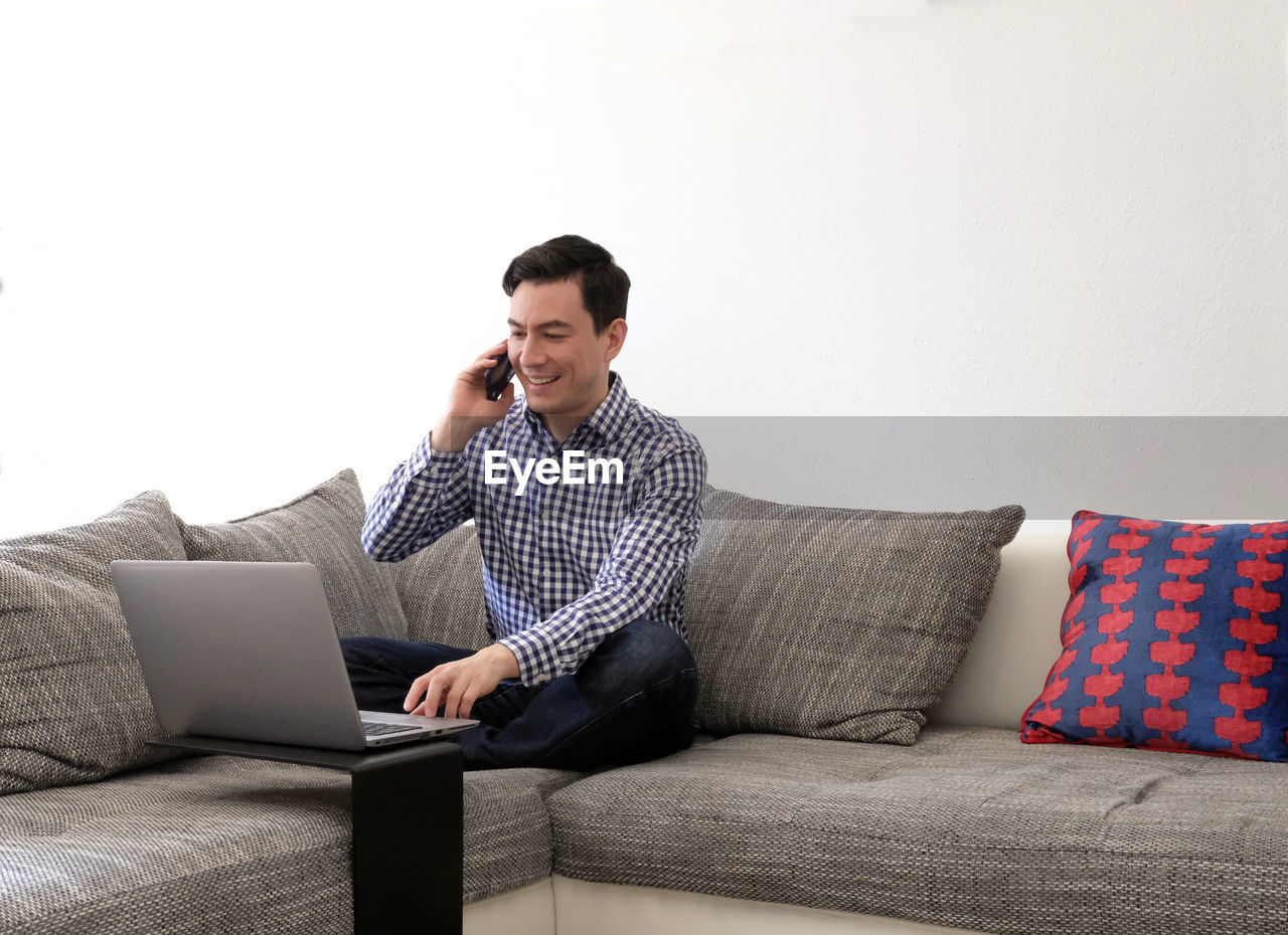 Man using laptop while sitting on sofa at home