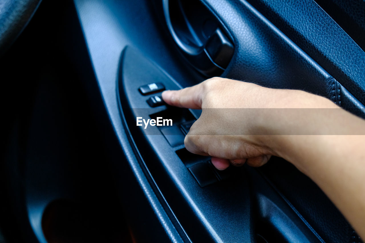 Cropped hand of person pressing button in car