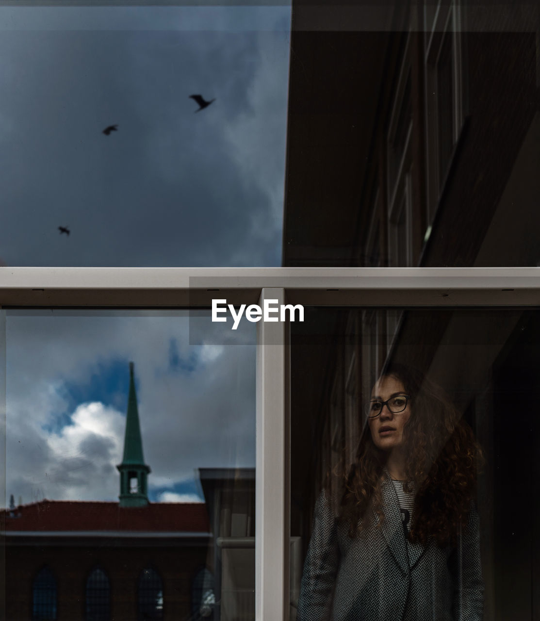 Young woman looking through window