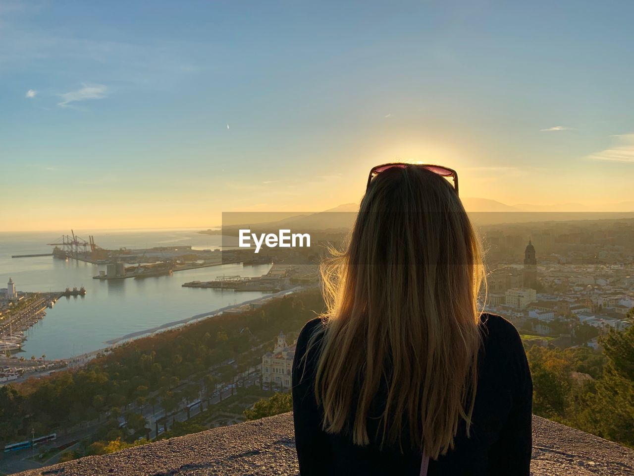 Rear view of woman standing against sky during sunset