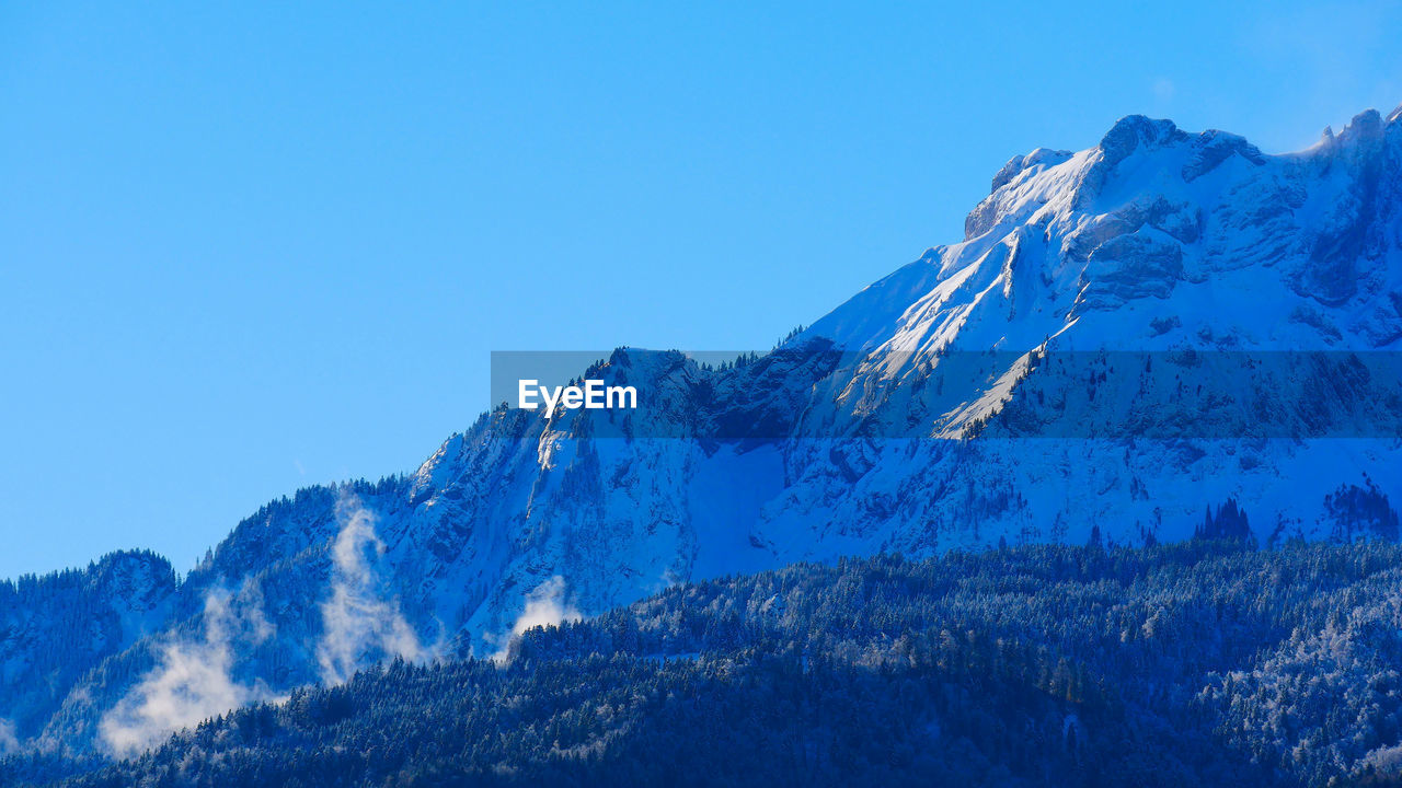 Scenic view of snowcapped mountains against clear blue sky