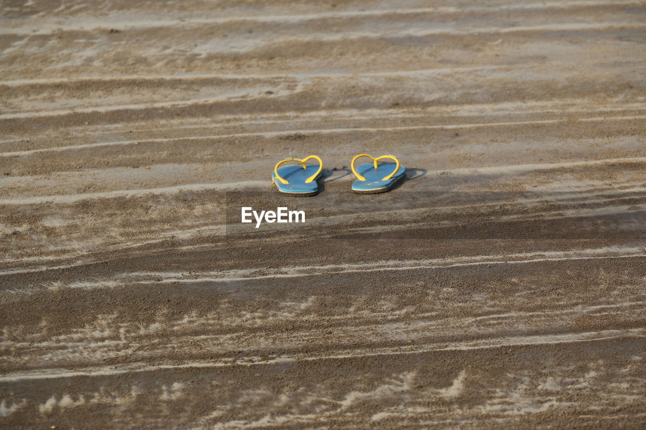 Slippers on sand during sunny day