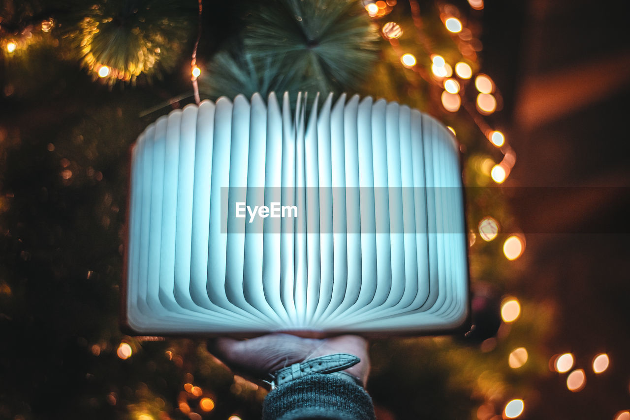 Close-up of hand touching illuminated lighting equipment at night