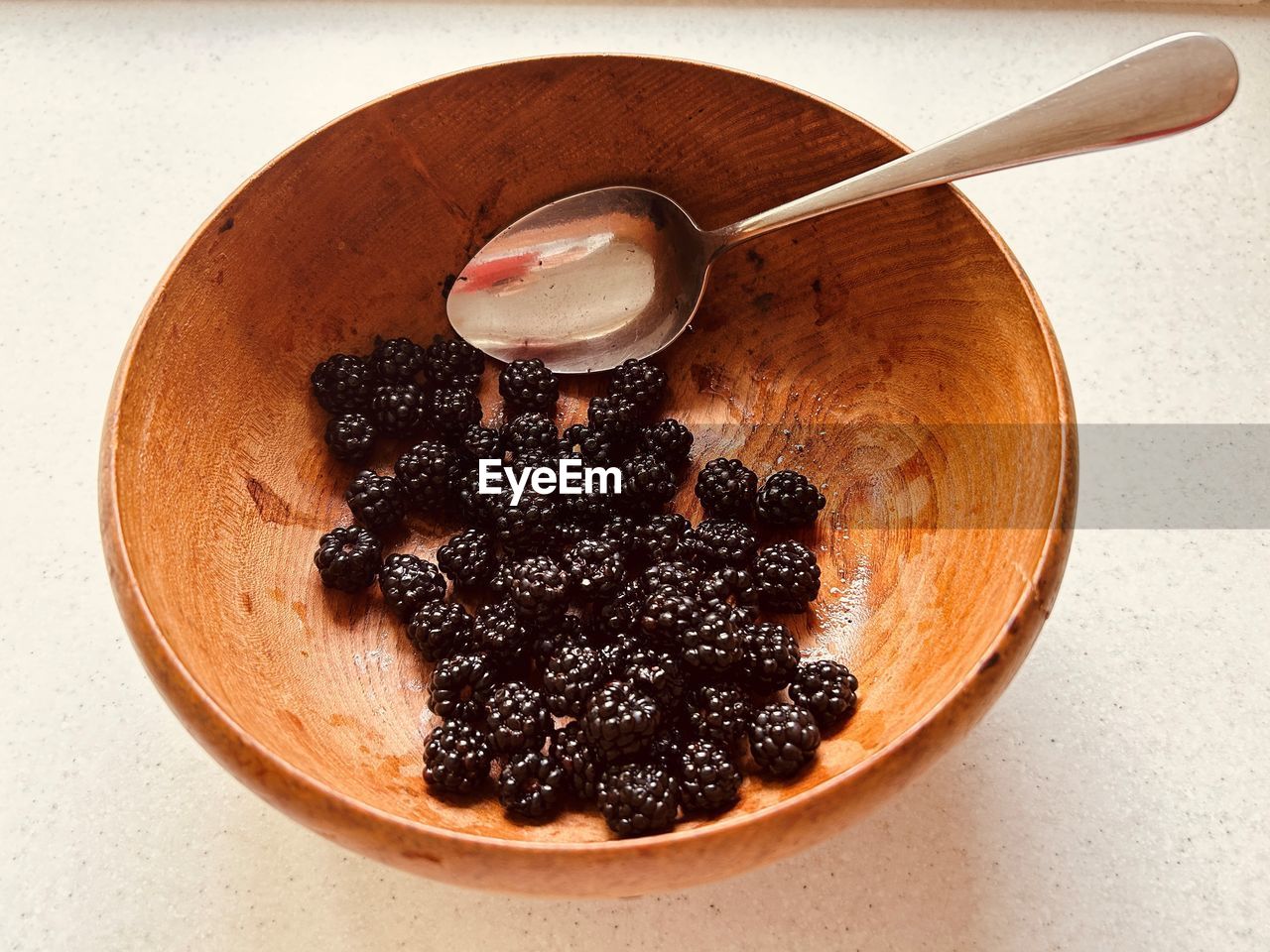 Blackberries and  stainless steel spoon in  wooden bowl. foraged, locally sourced, nutritious fruit.