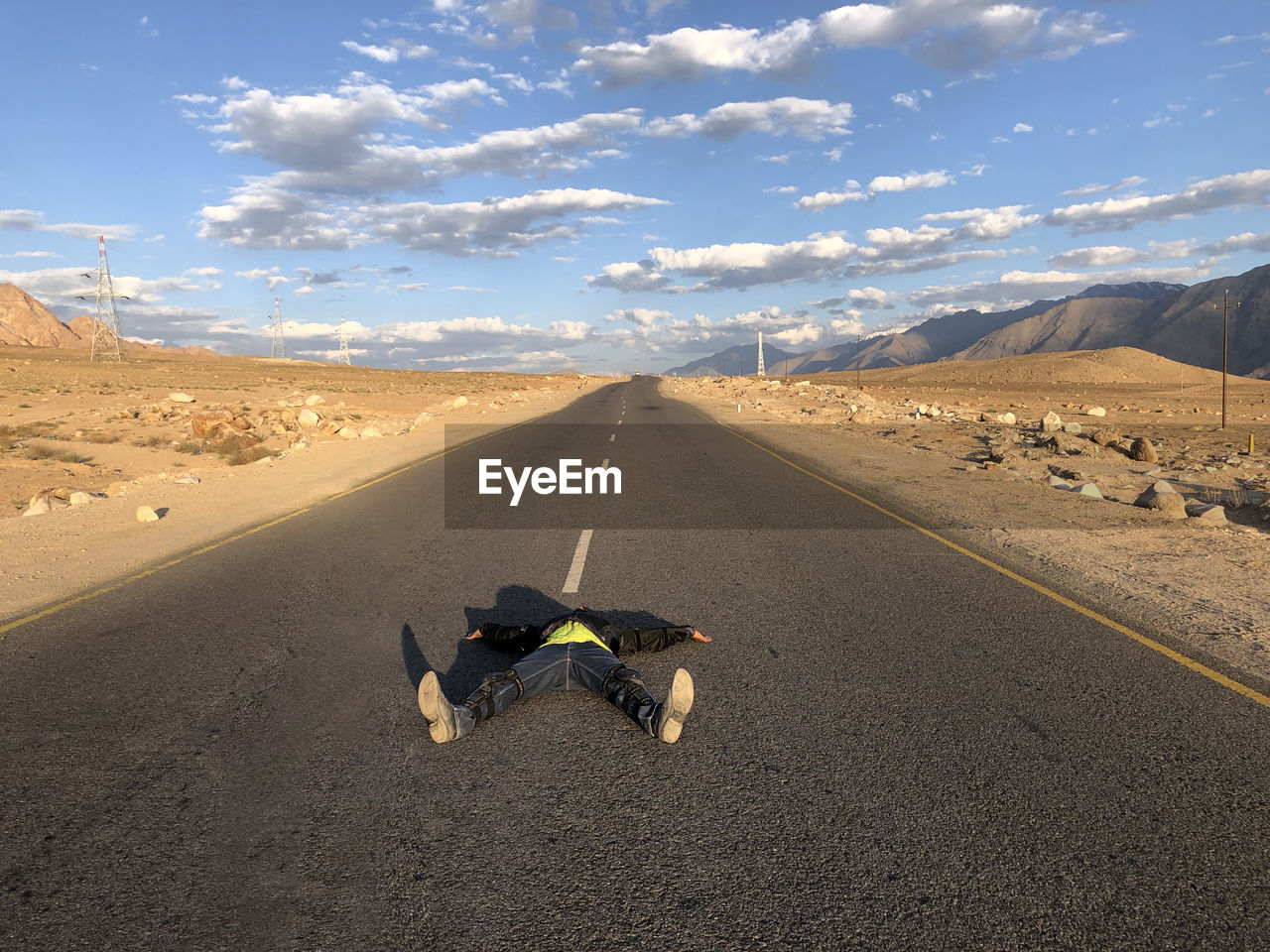 Teenage boy lying on road at desert