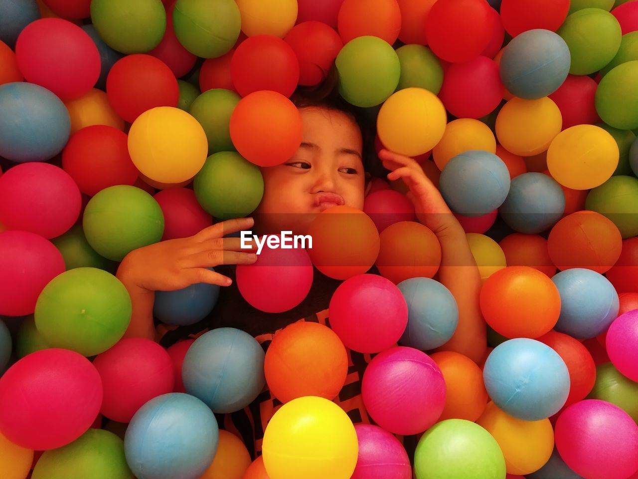 High angle view of girl amidst multi colored balls