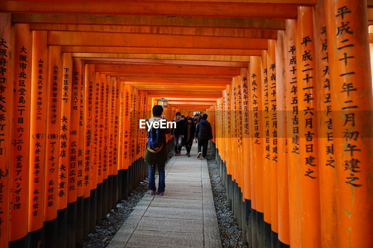 Narrow walkway along orange pillars with japanese script