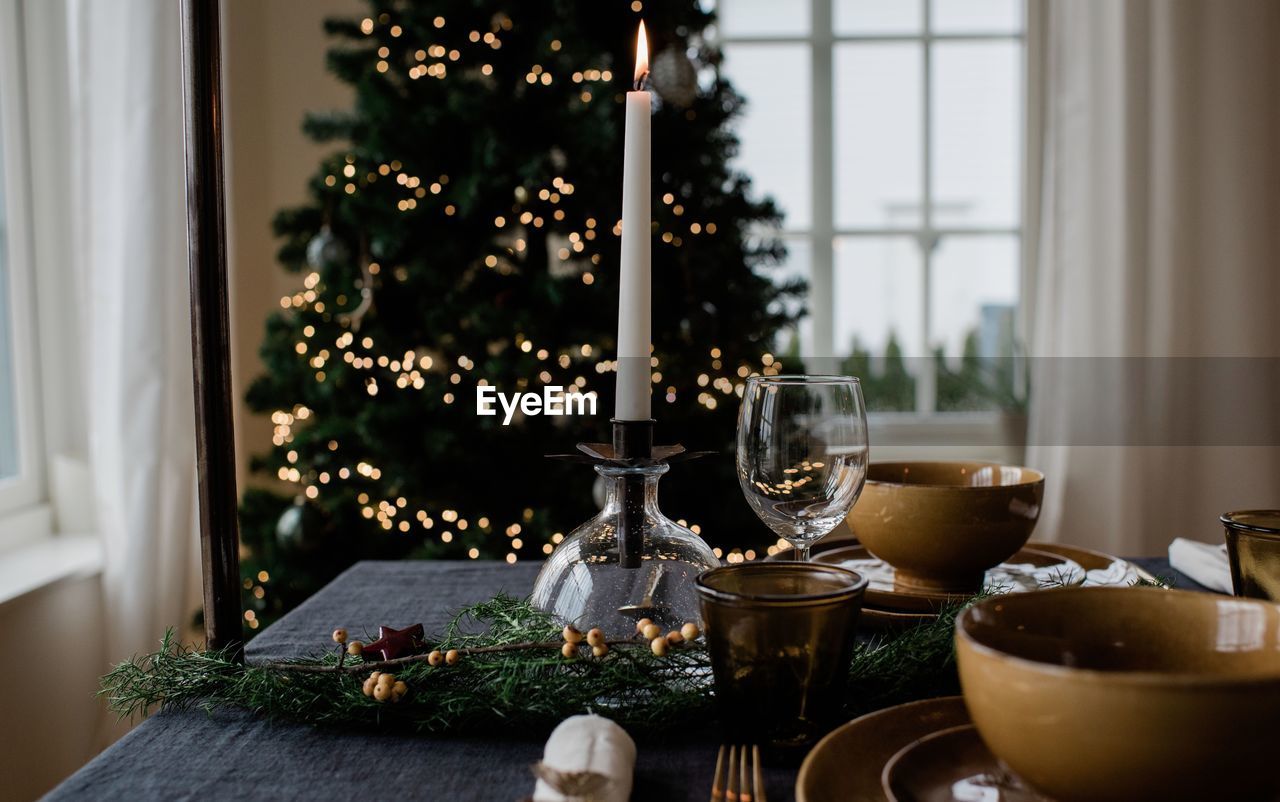 Lit candle on a festive decorated dinner table at christmas