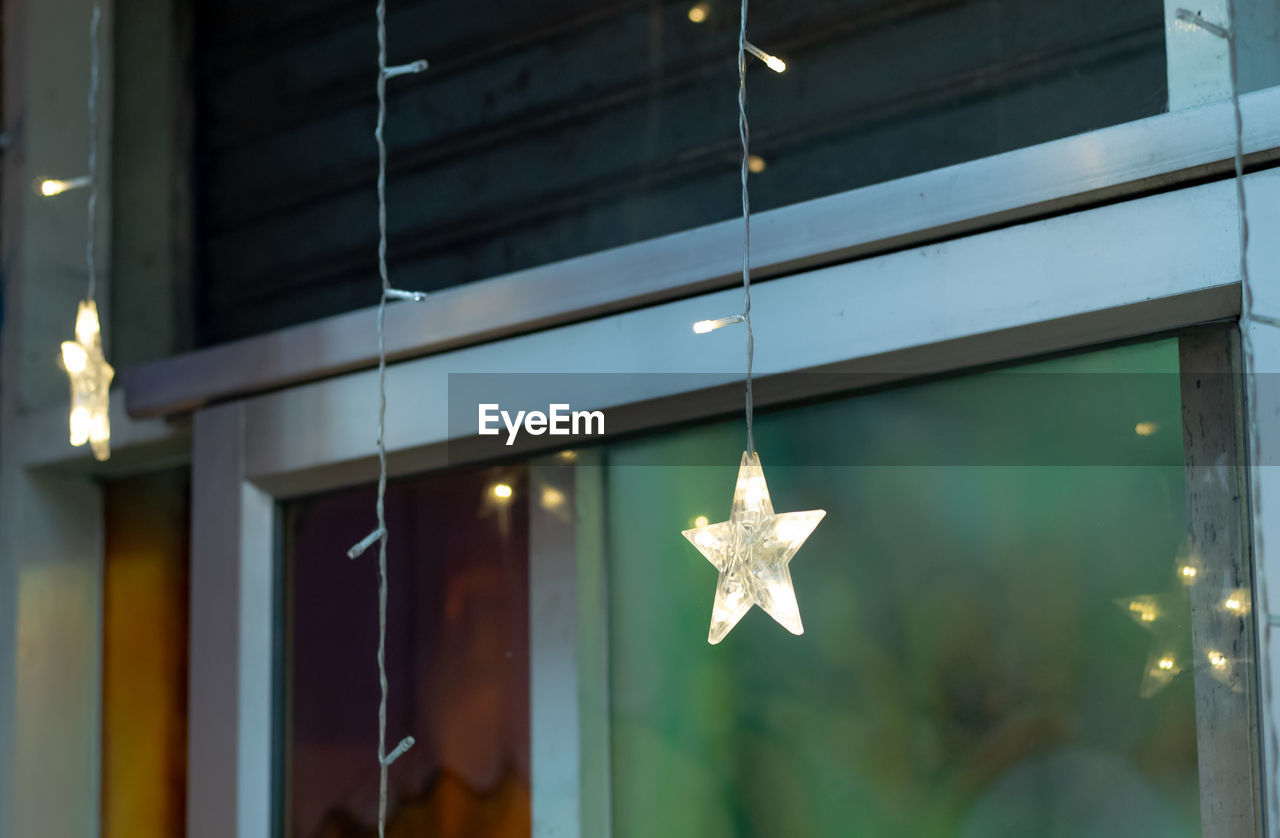 CLOSE-UP OF CHRISTMAS DECORATIONS HANGING FROM WINDOW