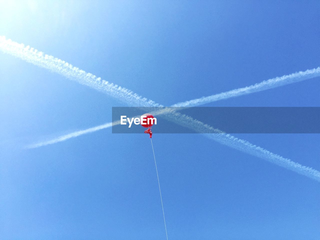 Low angle view of red balloon flying against blue sky during sunny day