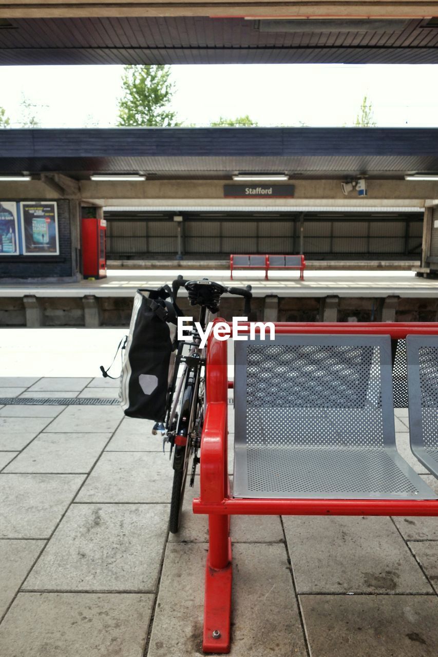 Bicycle parked by seat on railroad station platform
