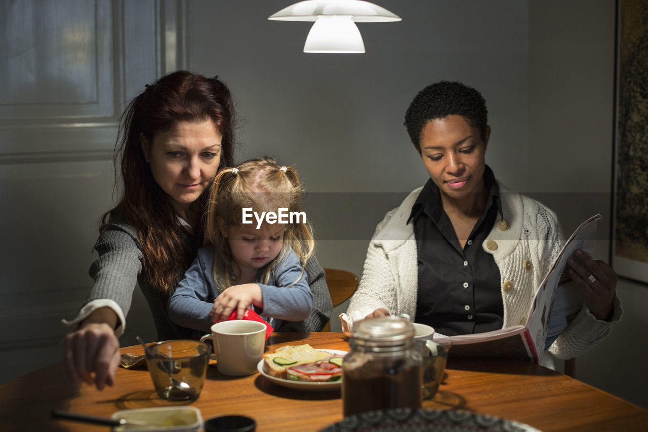 Girl and lesbian couple having breakfast at dining table