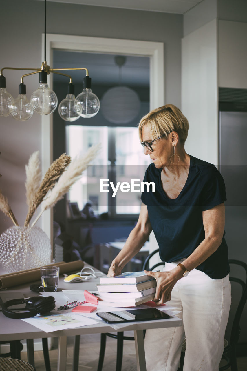 Woman with pile of books in home office