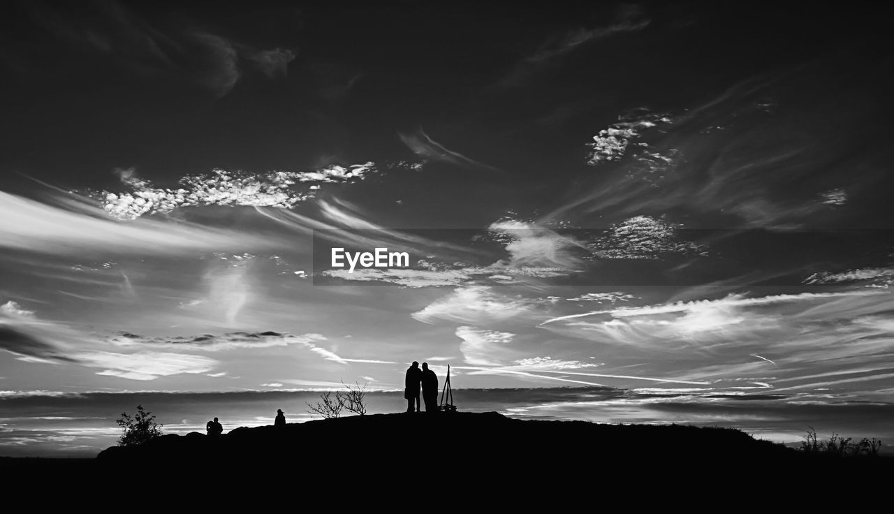 Silhouette people standing on mountain against sky during sunset