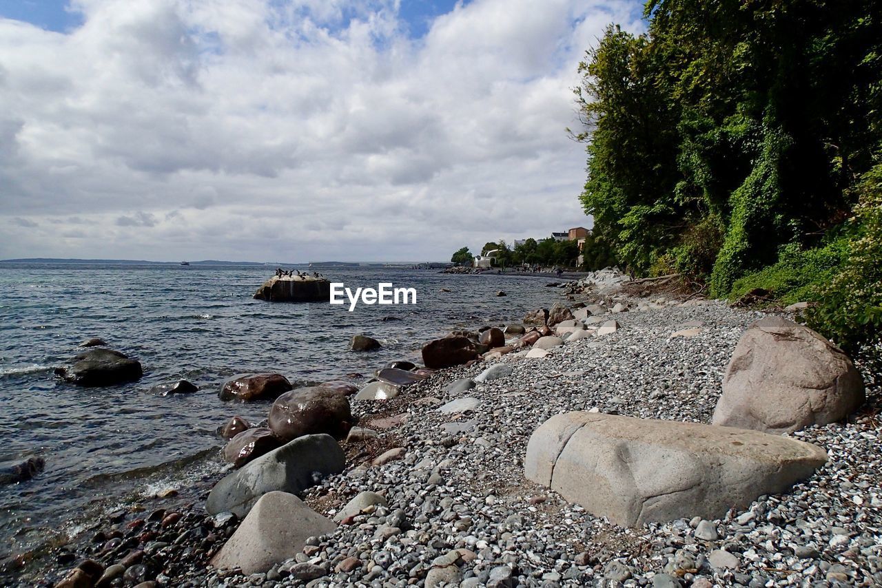 ROCKS BY SEA AGAINST SKY