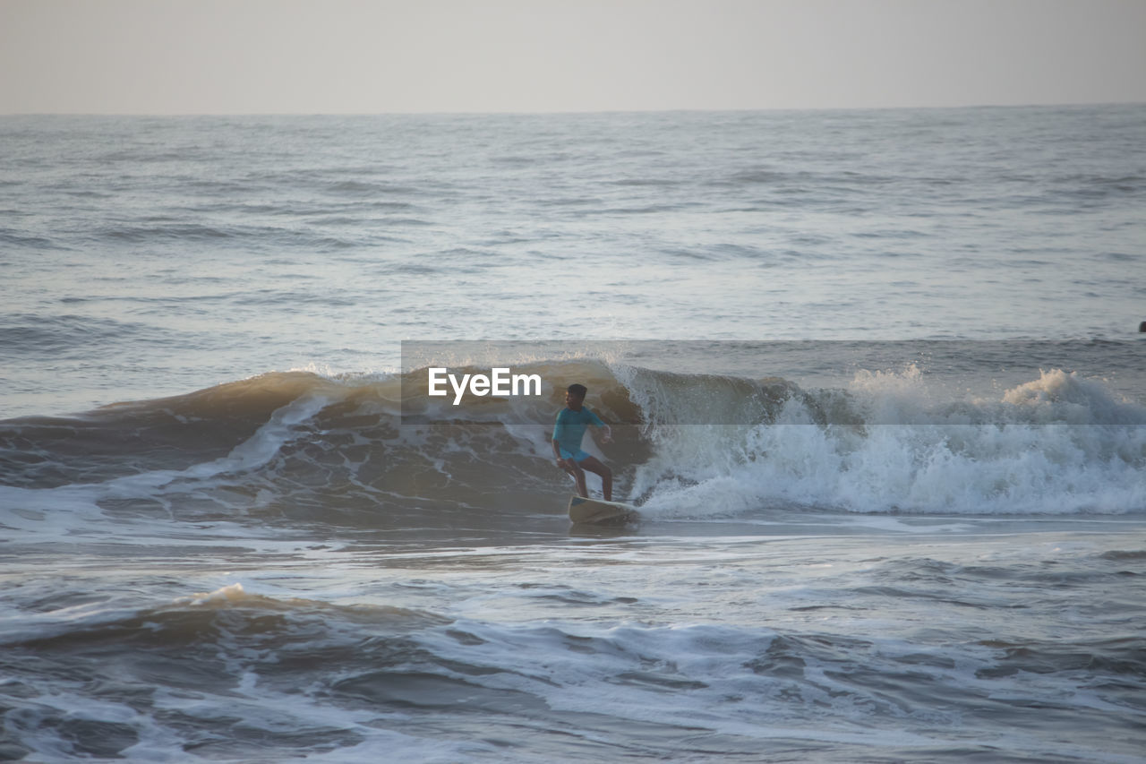 FULL LENGTH OF MAN ON SEA AGAINST SKY