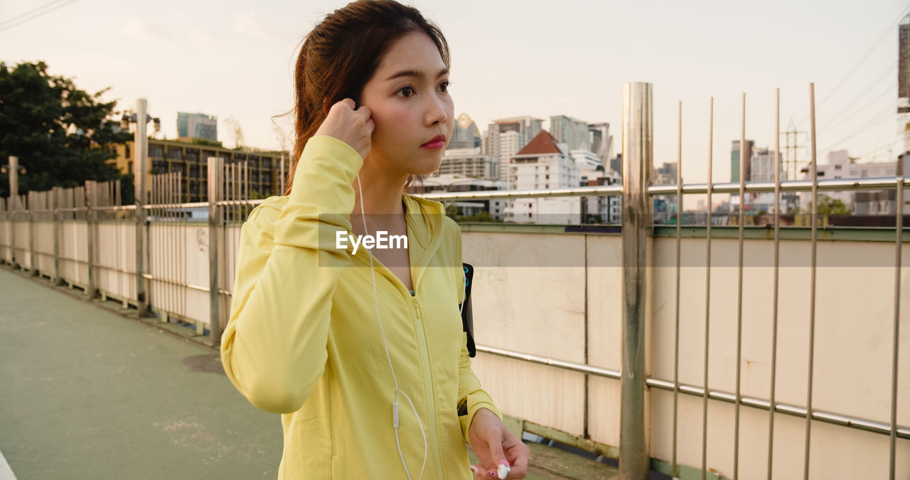 Young woman listening music while standing on road