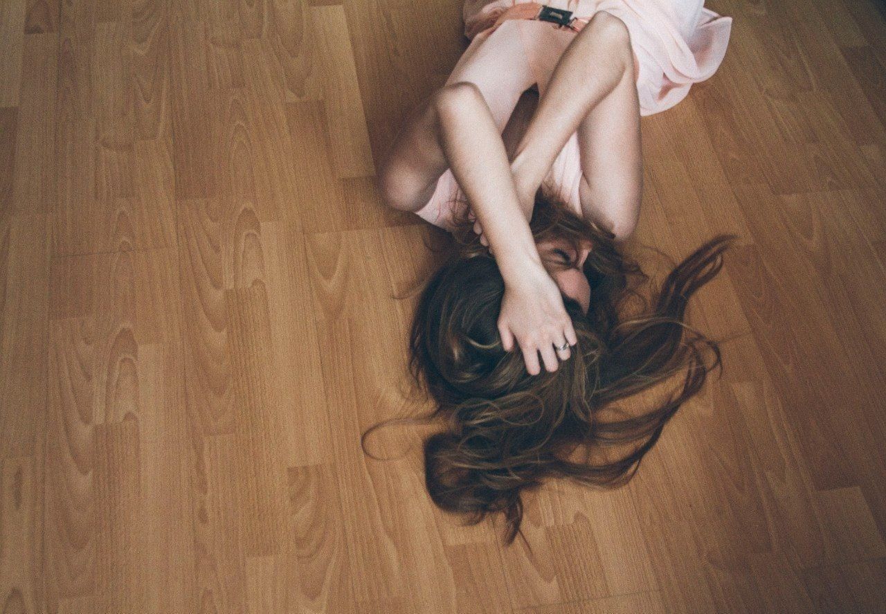 High angle view of depressed woman lying on hardwood floor