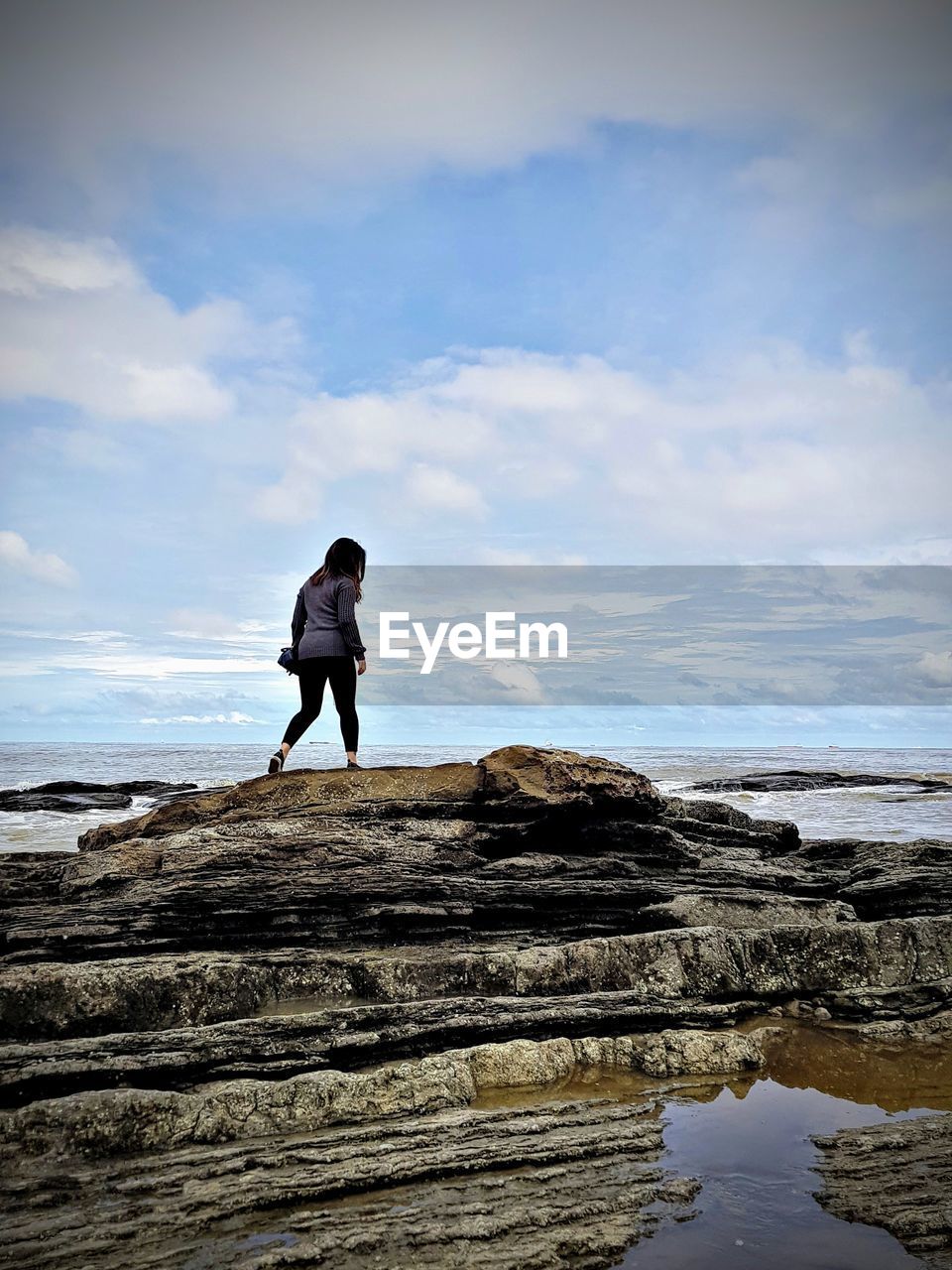 FULL LENGTH OF MAN STANDING ON ROCK AT BEACH