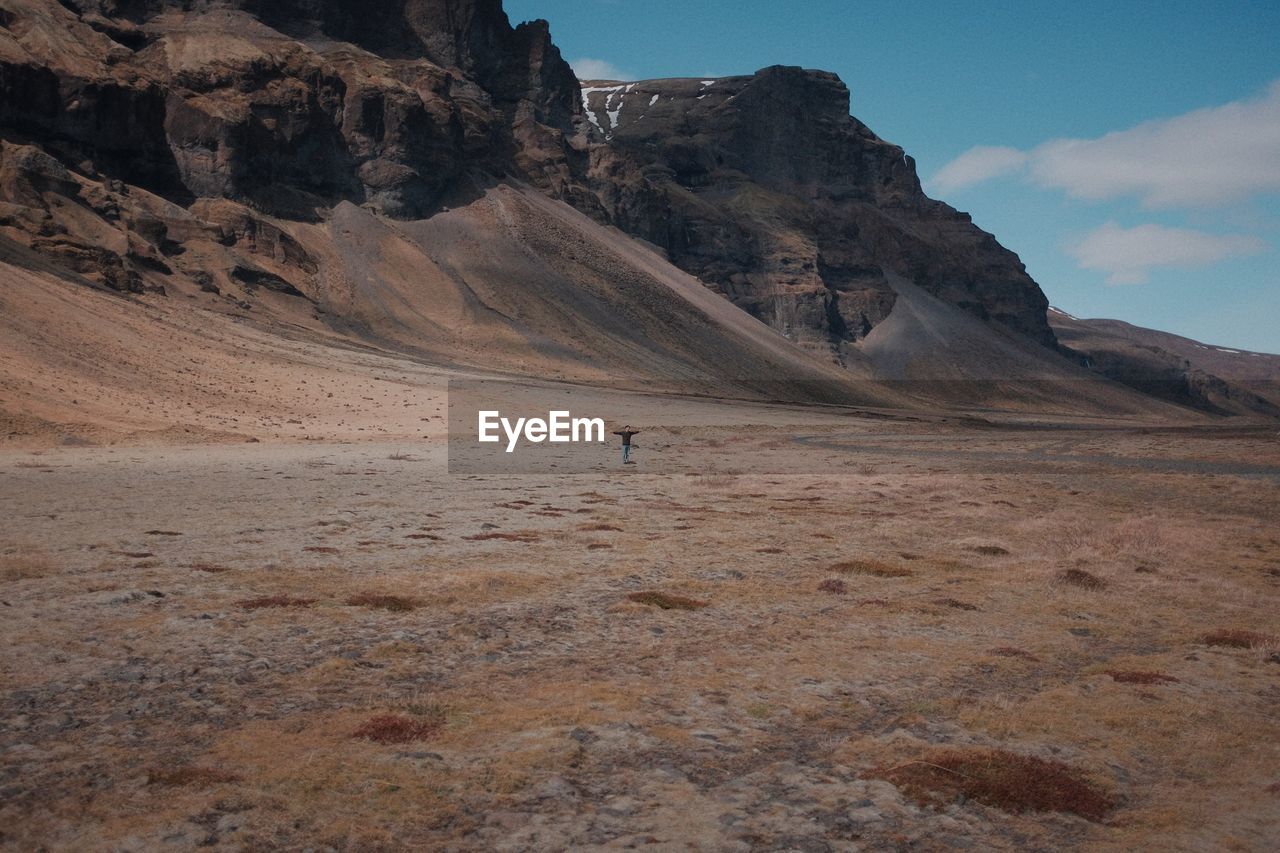 Distant view of person standing against rock formations