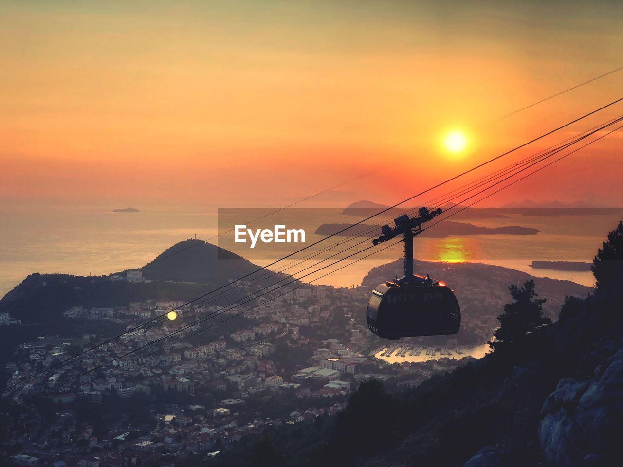 OVERHEAD CABLE CAR ON SNOWCAPPED MOUNTAIN AGAINST SKY DURING SUNSET