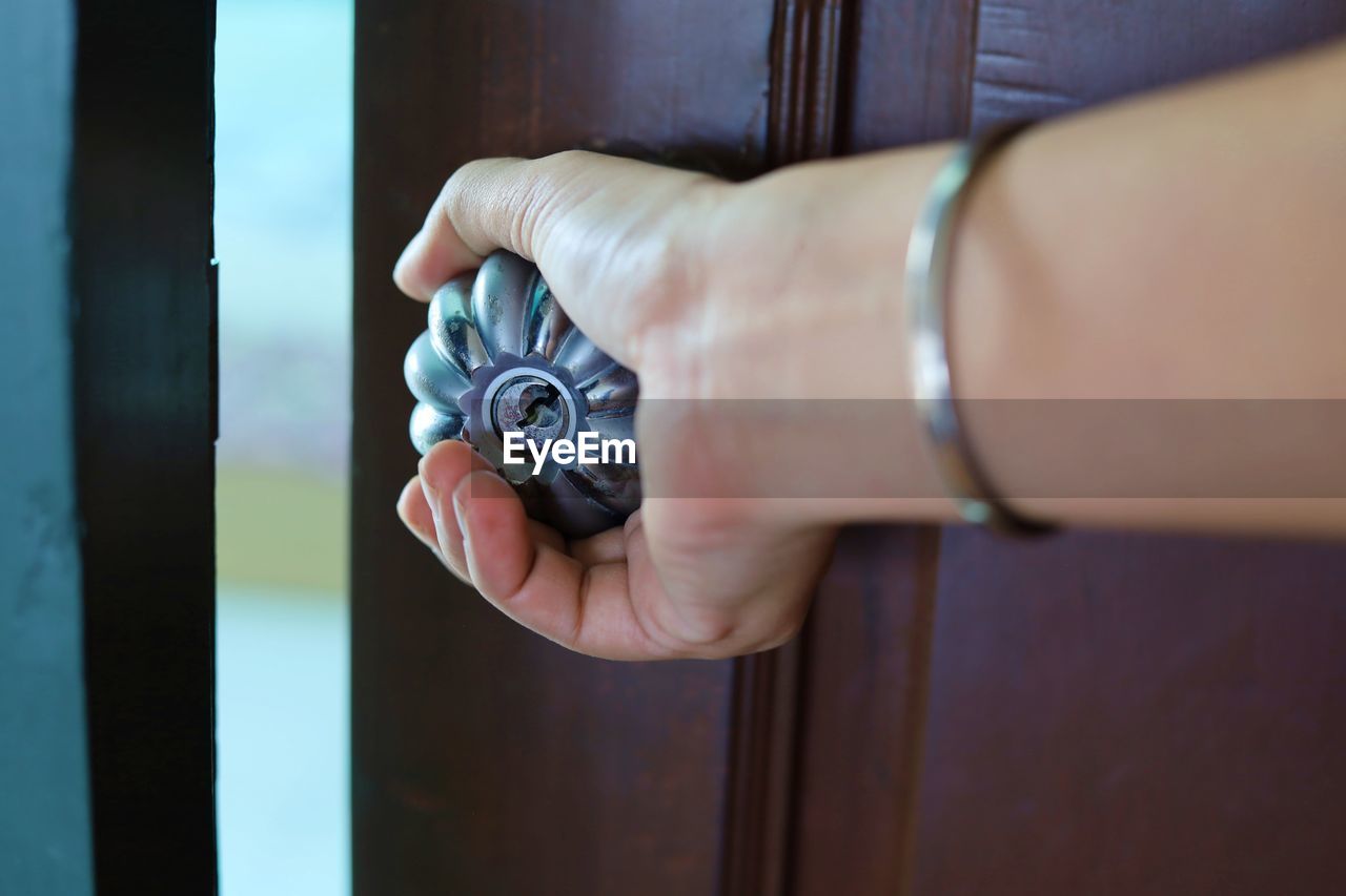 CLOSE-UP OF HUMAN HAND HOLDING DOOR