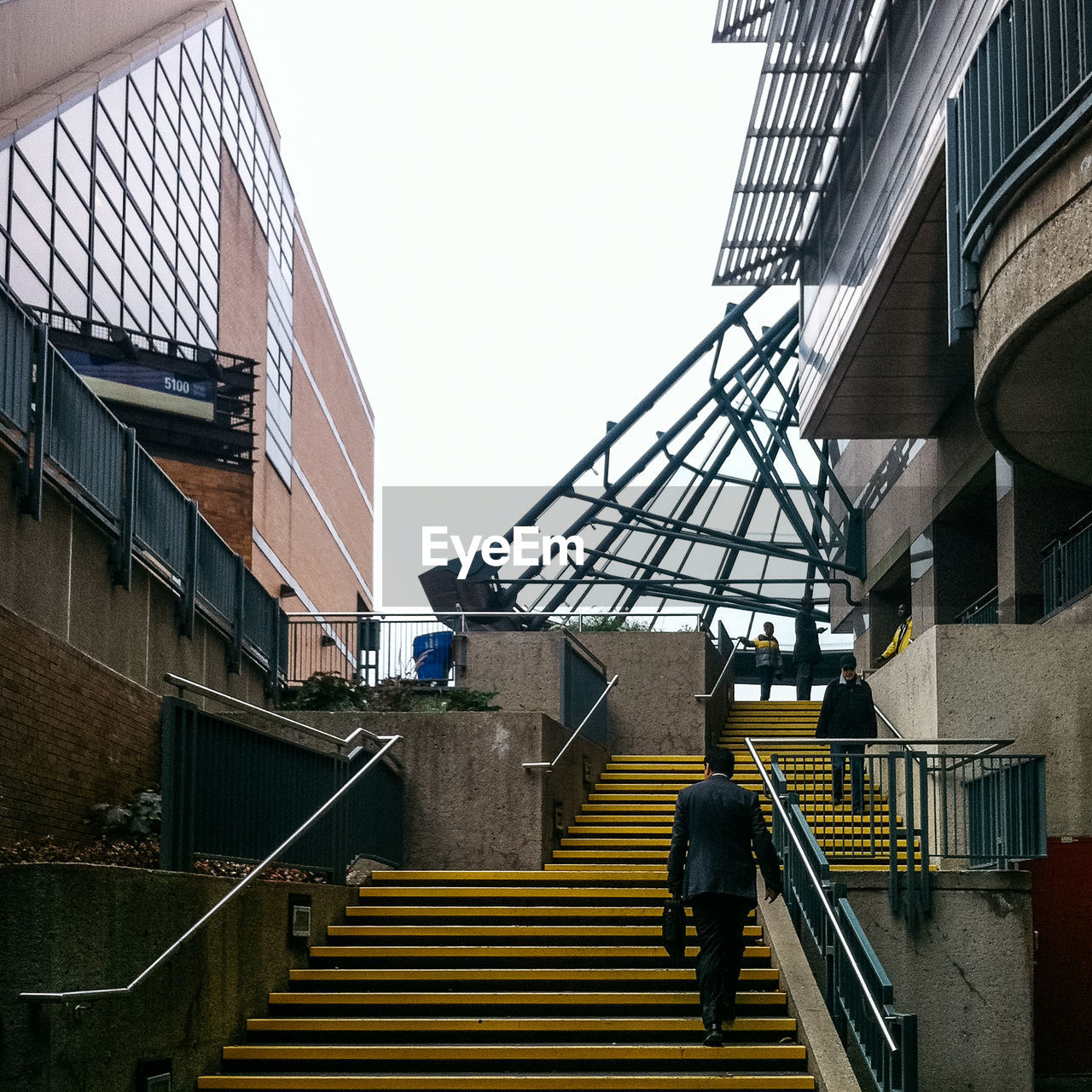 Rear view of businessman moving on staircase amidst buildings