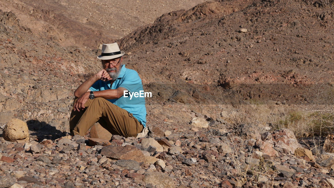 Senior man sitting on rock in the desert 