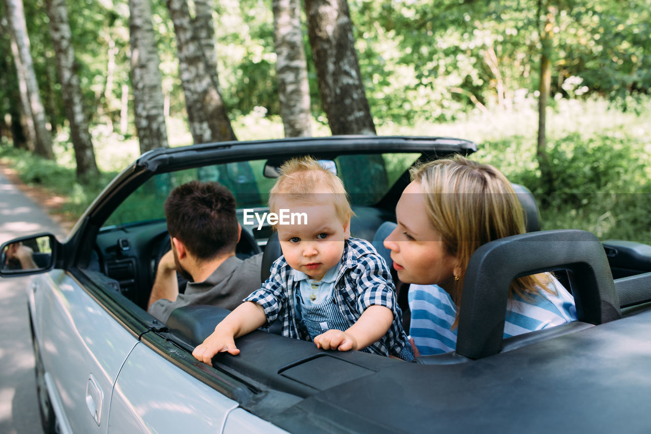 Mom, dad and little son in a convertible car. summer family road trip to nature