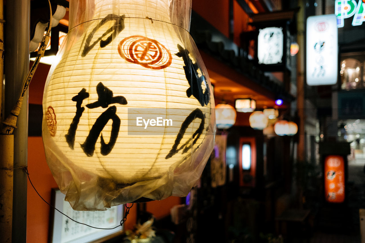 CLOSE-UP OF LANTERNS HANGING AT NIGHT