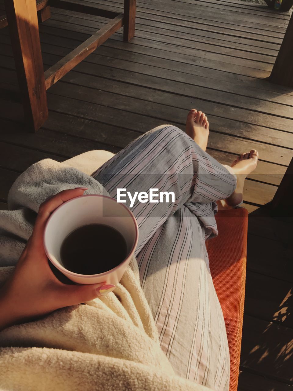 Low section of woman relaxing on wooden floor